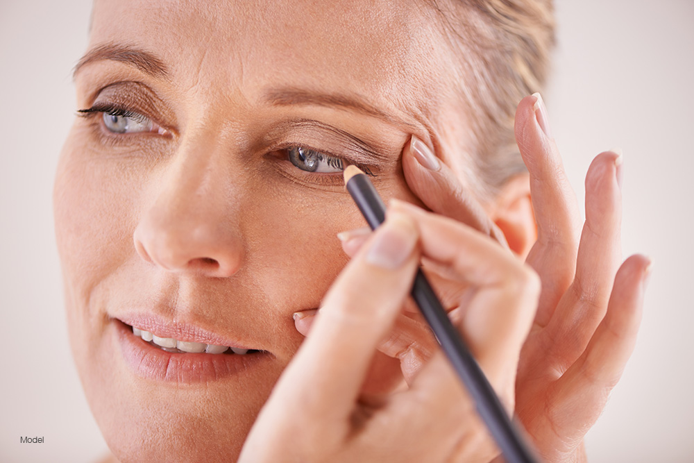 Mature woman putting on eyeliner